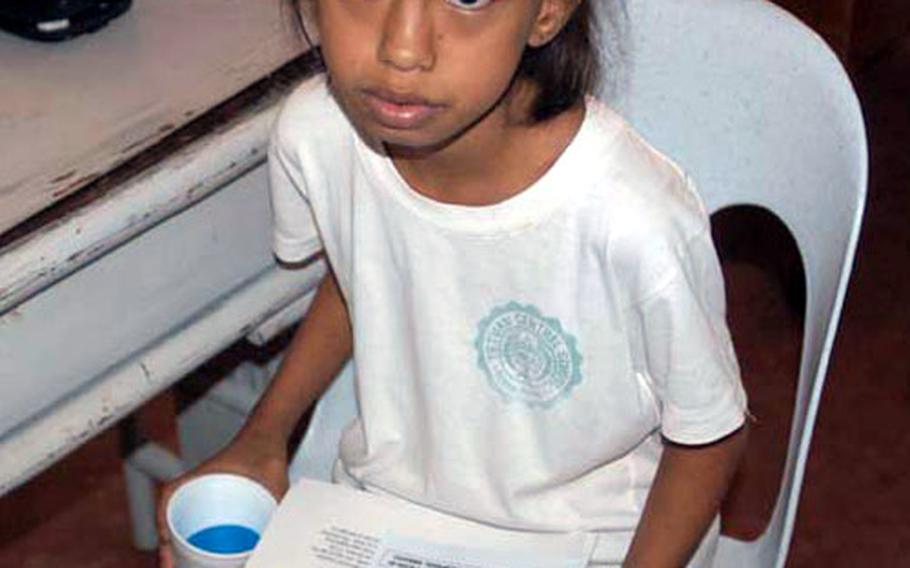 A young girl, waiting for a checkup, carries tips for preventing SARS during a Medical Civil Action Project, or MEDCAP, held by U.S. and Philippine forces near Zamboanga City in the Southern Philippines.