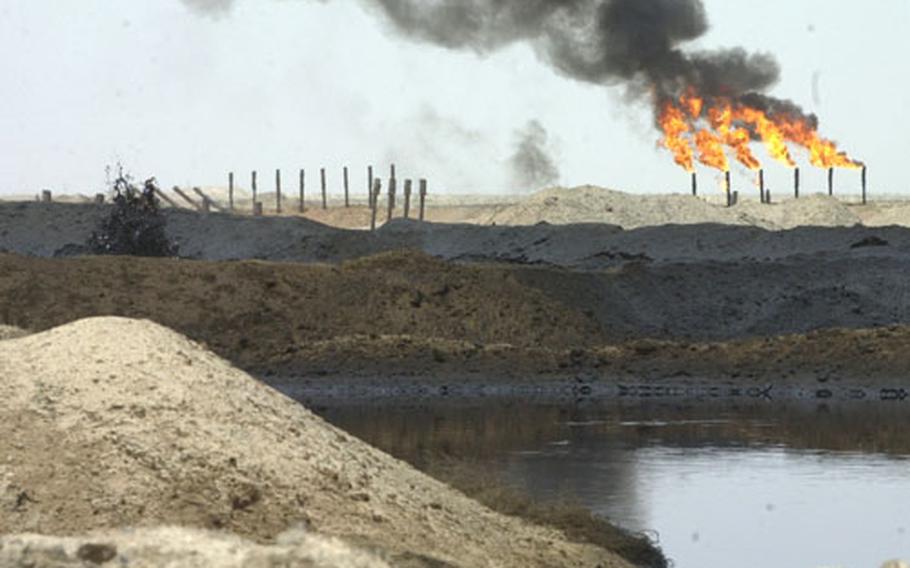 Lakes of bubbling crude surround an oil processing plant near Rumallah, Iraq, as necessary gas fires burn in the distance. The U.S. Army Corps of Engineers is overseeing a vast project to restore Iraqi oil and fuel production to help the local people.
