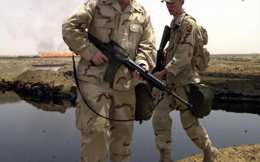 Spc. Joseph Feagin, left, and Spc. Damon Mehl stand beside a lake of oil outside Rumallah, Iraq.