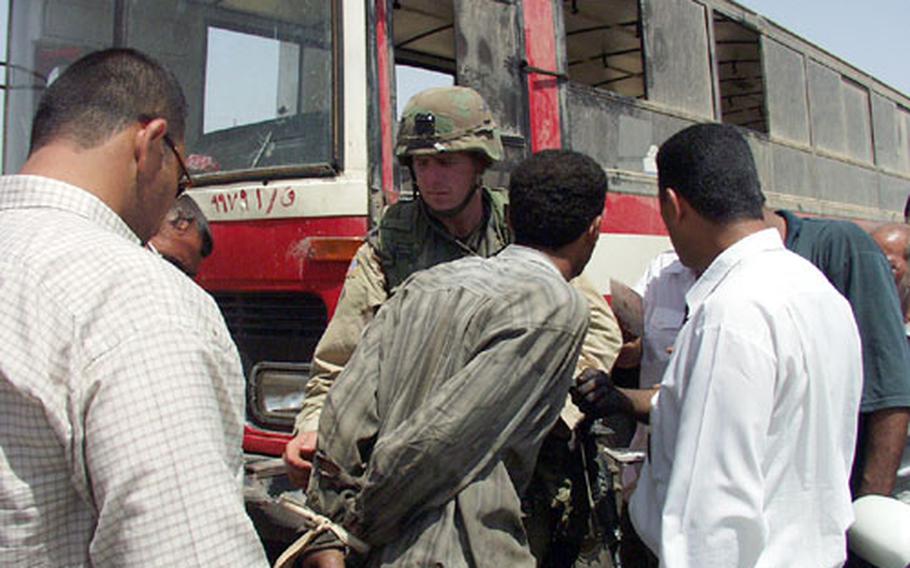 During a joint patrol with Iraqi police officers, Army Staff Sgt. Walter Vantichelt helps handcuff an Iraqi accused of stealing a city bus. The man later was released when his ownership documents proved accurate.