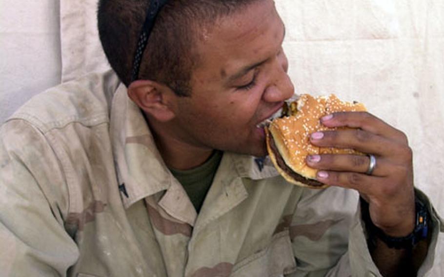 Lance Cpl. Santiago Tejada, 23, of Milwaukee, enjoys a well-deserved burger outside the Burger King tent on Camp Matilda, Kuwait. His Marine unit recently withdrew from Iraq.