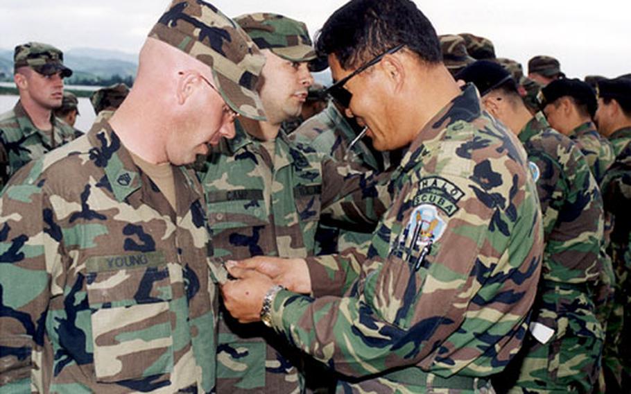 Veteran South Korean paratrooper Master Sgt. Sung Chang-woo of Korean Army&#39;s Special Forces pins Korean parachutist wings on a paratrooper from the U.S. Army&#39;s 4th Quartermaster Detachment during a wings-exchange ceremony.
