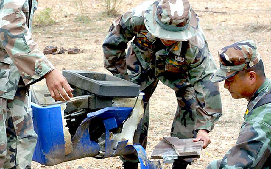 Royal Thai servicemembers pick up the remains of objects blown up as part of the demonstration Saturday.