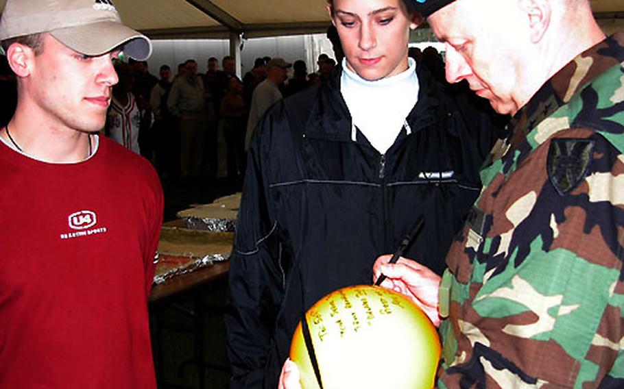 Maj. Gen. William E. Mortensen signs a ball for 2nd Lts. Jeremy Patten and Stacy Gervelis. Patten and Gervelis, members of the 529th Military Police Company, served with the 21st Theater Support Command in Antwerp, Belgium. The 21st TSC on Thursday celebrated its Army Superior Unit Award at Rhein Ordnance Barracks in Kaiserslautern, Germany. Patten and Gervelis said their unit took the ball with them on their mission as a reminder to not "drop the ball."