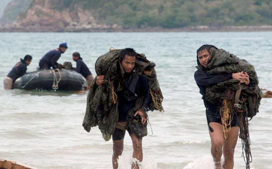 Royal Thai Navy explosive ordnance disposal team members leave a Zodiac combat rubber raiding craft for shore carrying parachutes Wednesday after jumping with U.S. Navy EOD personnel during a combined U.S.-Thai training jump during Cobra Gold in Thailand.