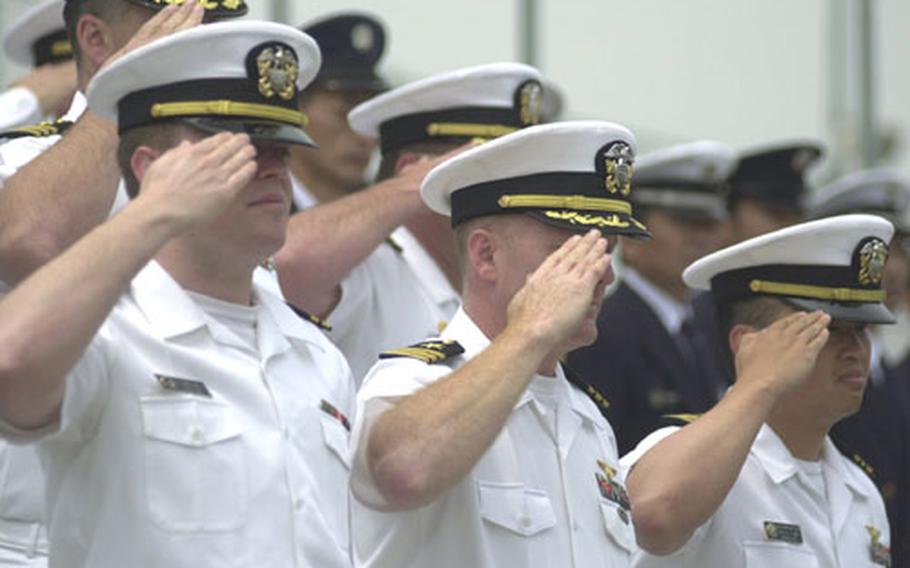 Officers at Atsugi Naval Air Facility salute as Taps is played.
