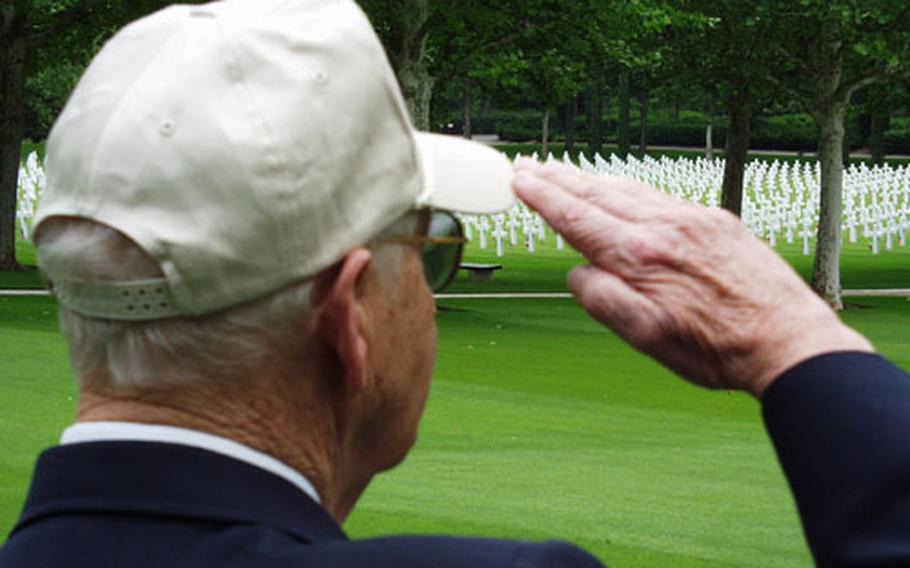 Peter Austin, a World War II veteran, salutes the flag during the playing of the national anthem at a Memorial Day Service at the Florence American Military Cemetery in Italy. Crosses marking the burial spots of thousands of his former comrades are in the background.