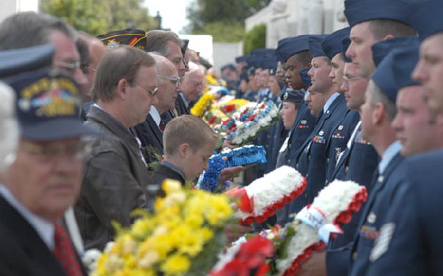 Active-duty service members, right, hand wreaths to representatives of 119 organizations that placed wreaths at the Cambridge American Cemetery during a Memorial Day ceremony Monday.