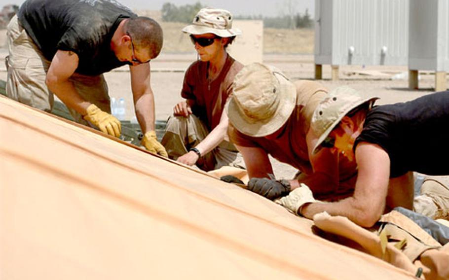 From left, Master Sgt. Rich Adkins, Lt. Col. Tracey Walker, Tech. Sgt. Richard Toumberlin and Master Sgt. Michael Schmidt stretch the canvas of a tent they are building at Kirkuk airfield, Iraq.