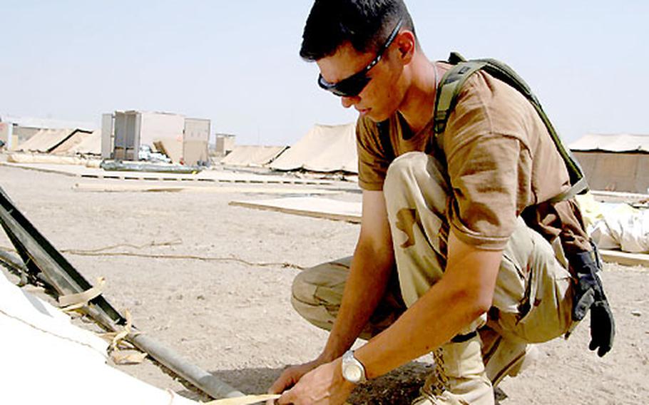 Airman 1st Class Darrel Dabeck ties down the side of a tent at Kirkuk airfield.