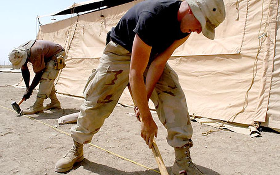 Airman 1st Class Tadd Wallace, right, and Master Sgt. Marshall Townsend hammer in stakes to support a tent they erected at Kirkuk airfield in Iraq. Members of the 506th Expeditionary Civil Engineering Squadron from McConnell Air Force Base in Wichita, Kan., and volunteers from other Air Force units stationed at the airfield are building a tent city with 194 billeting tents.