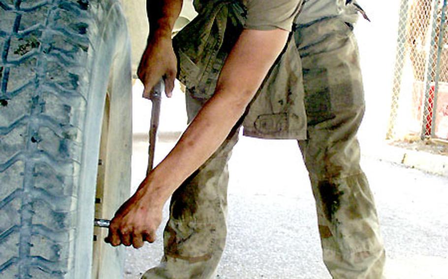 Pfc. Ross Scarbrough tightens the lug nuts on a Humvee wheel. Scarbrough and mechanics at V Corps’ Special Troops Battalion kept 800 vehicles in top shape during the Iraq war.