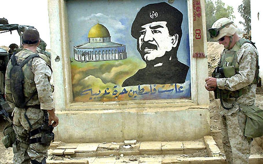 Marines stand at the gate of a suspected terrorist training camp outside of Baghdad on April 7. The mural of Saddam Hussein portrays him as protector of the Rock of the Dome, a sacred religious site in Jerusalem for Muslims.