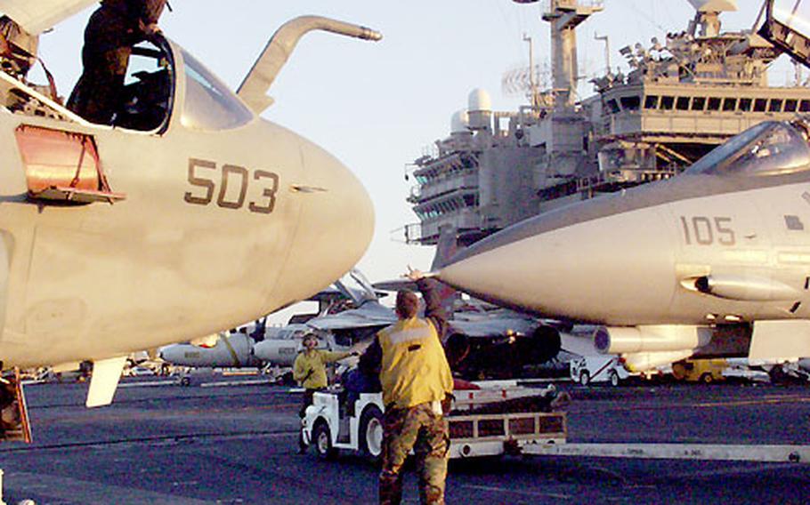 A sailor in an EA-6B Prowler, left, looks down at a fighter getting close to the aircraft while it’s being parked on the USS Kitty Hawk flight deck.