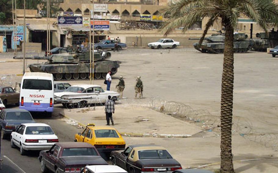 Three M1-A1 tanks and a platoon of 1st Armored Division soldiers guard a gas station in the Mansur district of Baghdad as drivers queue up to fill up.