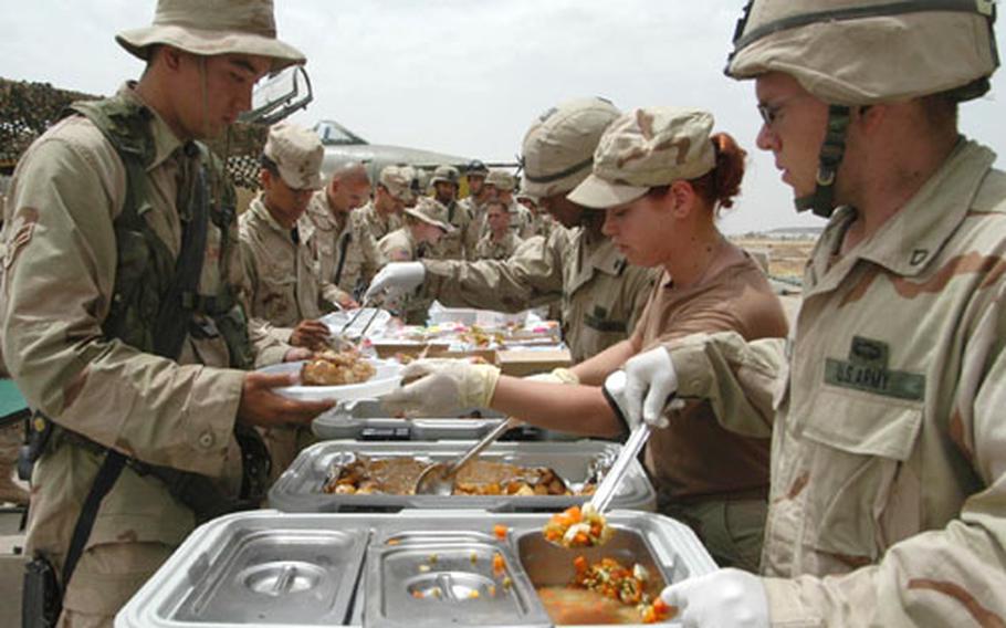 Pfc. Ty Starkey, right, of the 173rd Airborne Brigade, Airman 1st Class Dana Stanford of the 506th Expeditionary Services Squadron, and Sgt. Carlos Ramos of the 173rd serve up chicken, potatoes and vegetables to soldiers and airmen at the belated Memorial Day picnic at Kirkuk airfield, Iraq. 4000 servings were prepared for the day&#39;s feast.