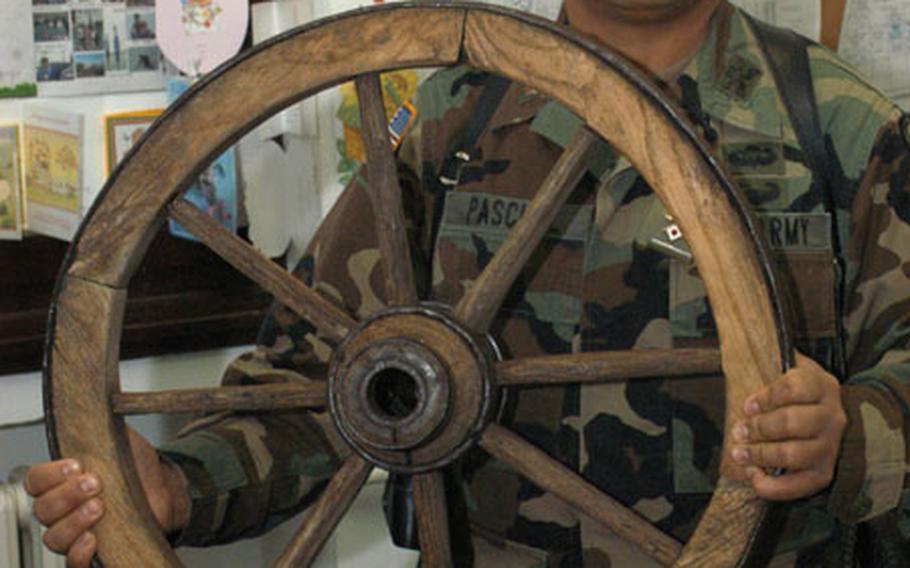 Maj. M.R. "Donel" Pascual of Headquarters and Headquarters Company, 35th Infantry Division, proudly displays the wagon wheel representing the Broken Spoke Award he won. Following a funny presentation during Saturdays&#39; Battle Update Brief meetings at Eagle Base of the biggest mess-ups of the week, some as erroneous as being tall or short in stature, or just gullible, the award is given out every week. The presentation draws standing-room-only crowd to the morale-building and stress-relieving event.