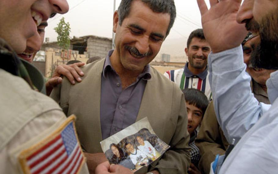 Children bring smiles to fathers&#39; faces as Maj. Christopher Schrieks, left, of the 404th Civil Affairs Battalion out of Fort Dix, N.J., shows a photo of his children to men in the village of Garawe, Iraq, on Saturday. Schriek&#39;s civil affairs team was doing an assessment of the Kurdish village, checking on water, sewage, schools and medical care facilities.