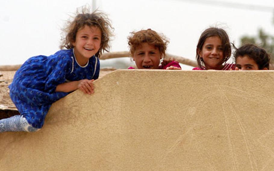 Four young Kurdish girls in Garawe, Iraq, are a little shy, climbing on and peeking over the school wall when an American civil affairs team paid a visit to their village.