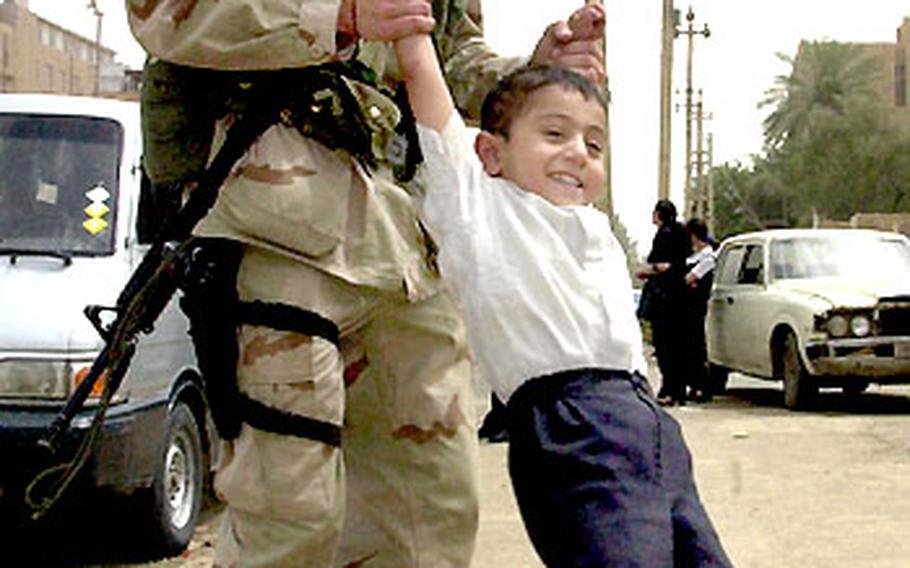 Pfc. Jeremy Coop, 19, of New Carlisle, Ohio, swings an Iraqi boy around Monday on a Baghdad street.