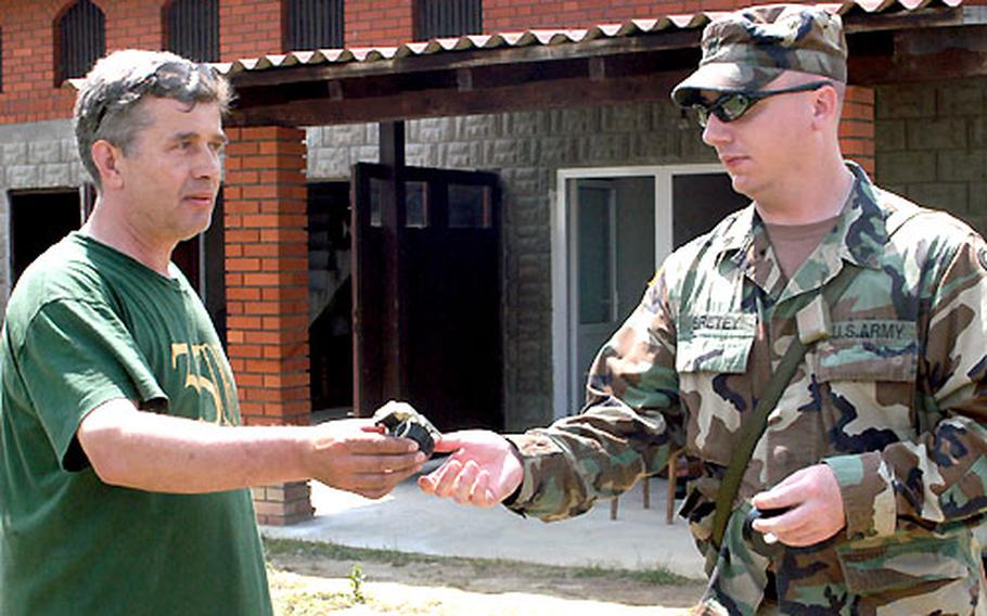 Brcko resident Marko Mendes turns in a hand grenade left over from the 3½-year Bosnian war to Sgt. Shane Bretey of Troop B, 1st Squadron, 167th Cavalry Regiment.