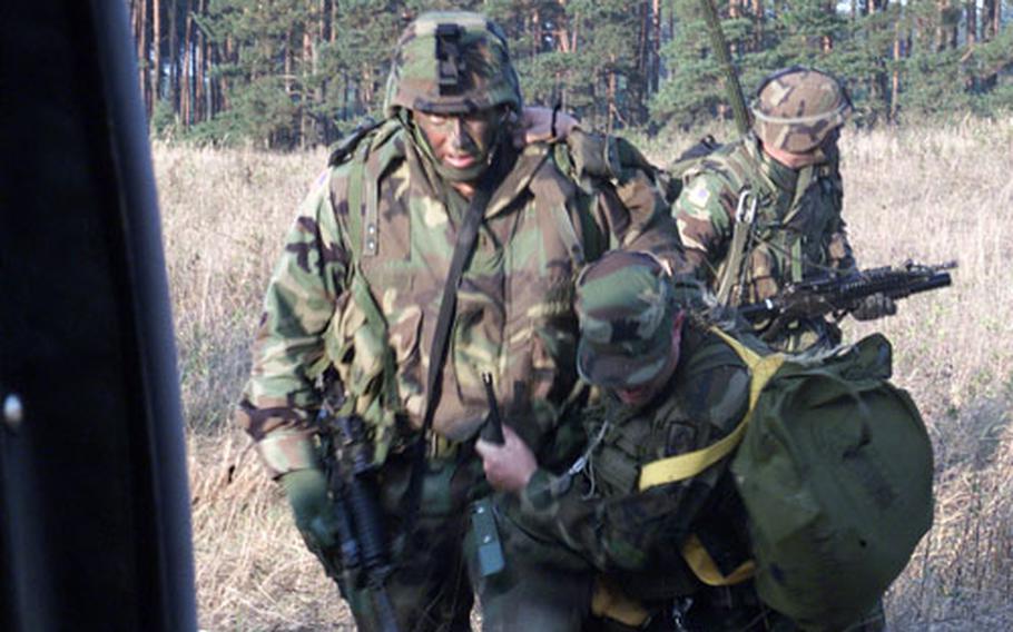 In this file photo from September 2002, Sgt. 1st Class Daniel Pinion helps a 'wounded pilot,' Chief Warrant Officer Shaun Cusic, into a Black Hawk helicopter during combat search-and-rescue training as part of the Victory Strike exercise near Miroslawiec Air Base, Poland.