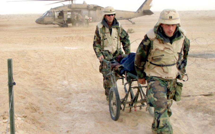 Company Commander Capt. Sean Farley, foreground, and Maj. Ronald Krogh, 212th executive officer, bring in a casualty in the early days of the fighting.