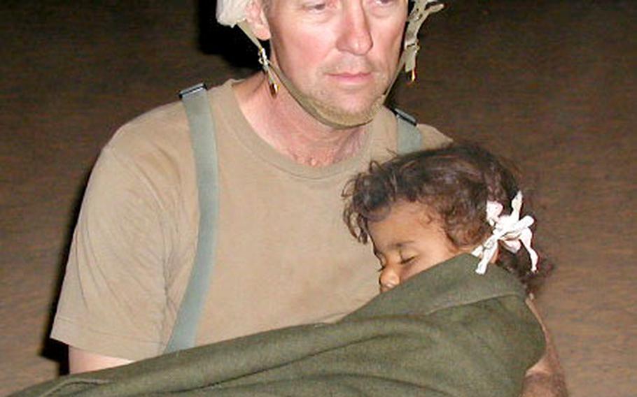 Maj. Ronald Krogh, 212th Mobile Army Surgical Hospital executive officer, cradles an Iraqi girl in the middle of the night. MASH personnel treated the girl&#39;s family of six after they were slightly wounded in the cross-fire between U.S. troops and Iraqi forces during the first days of Operation Iraqi Freedom.