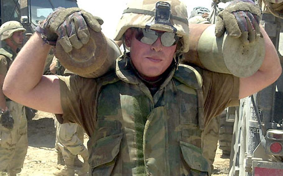 Pfc. Bryan Kirkland of the 41st Field Artillery Brigade shoulders two Iraqi artillery shell propellant bags at Red Rocket.