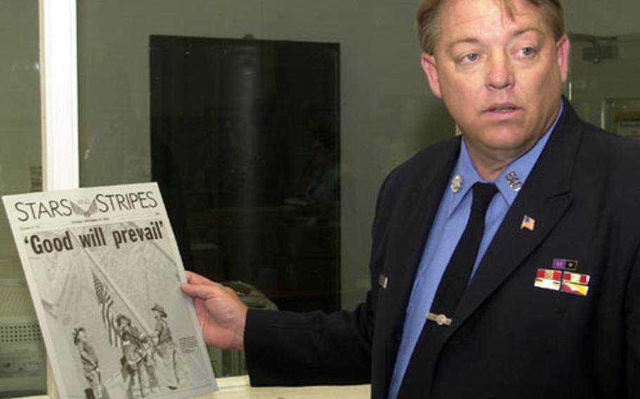 New York City firefighter Ray Pfeifer holds up a plate of the September 13th, 2001, edition of Stars and Stripes while touring Stripes facilities on Tuesday.