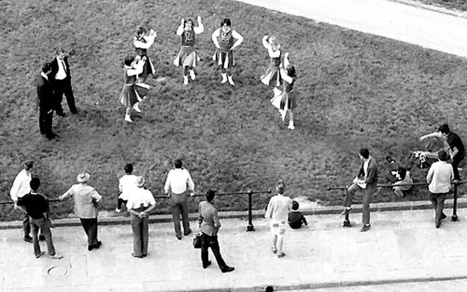 Locals and tourists take in the unusual sight of American cheerleaders at the Leaning Tower of Pisa.