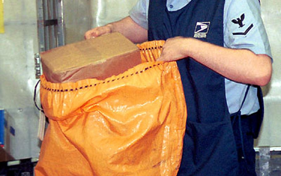 Petty Officer 3rd Class George Perry, a clerk at the Post Office, at Naval Air Station Keflavik, Iceland, unloads a package from a bag of mail from the previous night’s flight.