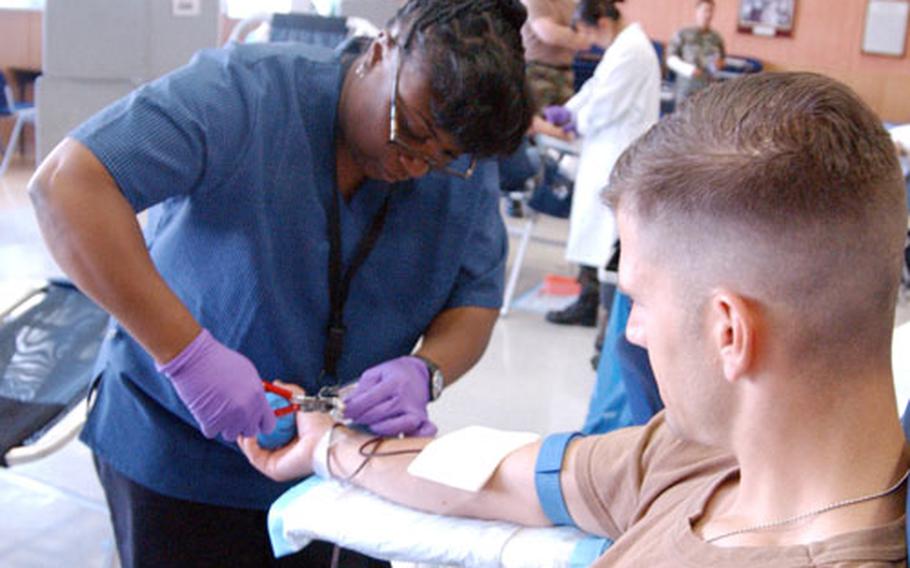 Spec. Craig Thompson gives blood while phlebotomist Peaches Tucker attends to him at a blood drive Wednesday at Landstuhl Army Regional Medical Center. "I just like to donate, knowing that it will help someone else," Thompson said.