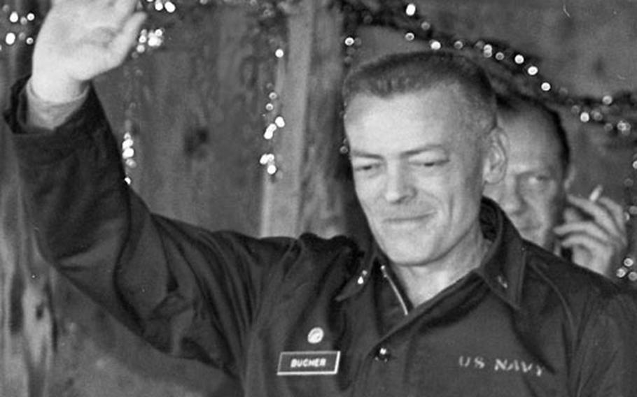 A haggard-looking Cmdr. Lloyd Bucher, just released from North Korea after 11 months in captivity, waves as he arrives for a press conference in the NCO Club at the U.S. advance camp near Panmunjom.