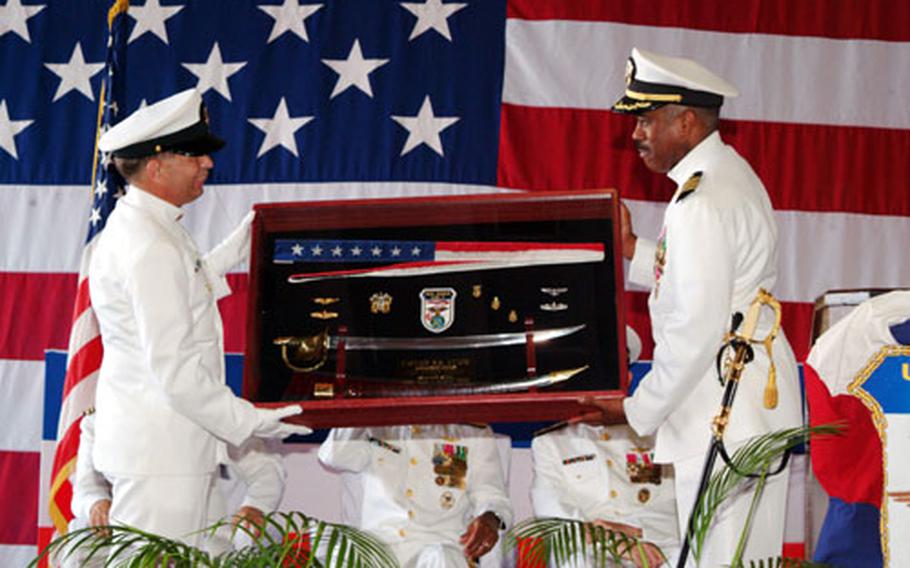 Command Master Chief Kevin Haun presents Capt. Ronald R. Evans with a shadow box containing the ship’s commissioning pennant and other memorabilia during the USS Essex change of command ceremony held last week. Evans was relieved as commanding officer by Capt. Jan M. van Tol.