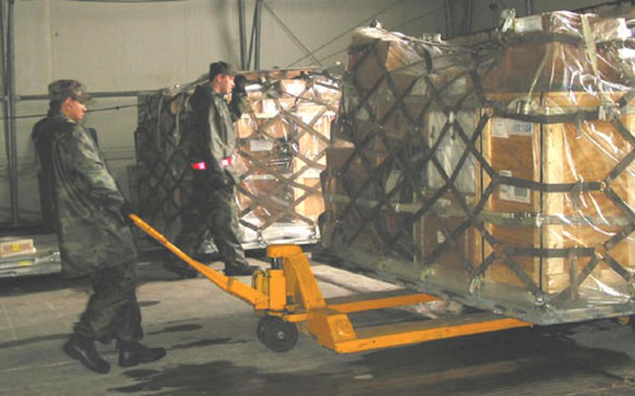 Senior Airman Rene Solis (front) and Senior Airman Brendon Borne, 603rd Air Control Squadron material control technicians, move a pallet filled with equipment in preparation for the 2003 NATO Air Meet to Poznan, Poland.