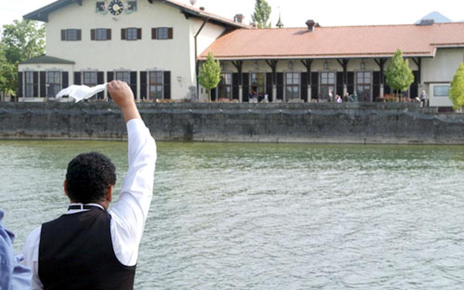Fernando Ugarte, a waiter for 14 years at AFRC Chiemsee&#39;s Lake Hotel waves as the farewell boat cruise prepares to dock Tuesday.