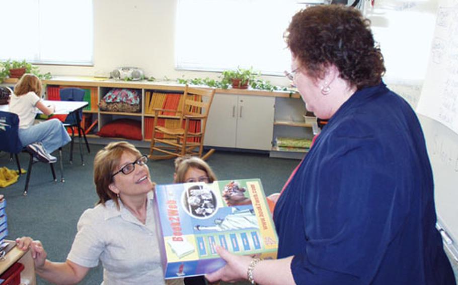 Myrna Moore, a gifted-program instructor at Aviano Elementary School in Italy, delivers school supplies to Susan Sajo, who is on her knees playing with the children. Sajo teaches a combination class of third-, fourth- and fifth-graders.