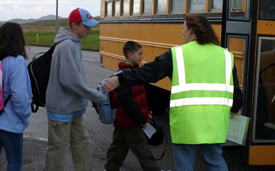 A bus monitor helps students safely board the bus to school. Students will have to adjust to a new scheduling program this year.