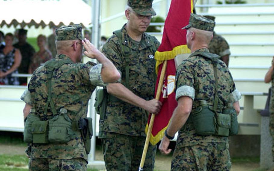 With the passing of the Marine Corps colors, Brig. Gen. James F. Flock, right, officially assumes command of Marine Corps Base Camp Smedley D. Butler from Brig. Gen. Timothy R. Larsen, middle. Sgt. Maj. Jeffery Green, left, renders a salute to the outgoing and incoming commanding generals while waiting to take the flag from Flock.