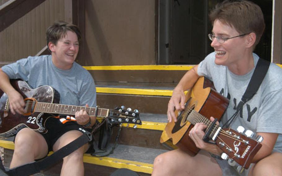 1st Lt. Sarah Kuhaneck, left, and Capt. Nancy Martin play guitars at Eagle Base, Bosnia and Herzegovina. The two have recorded a CD to remember the good times during their Bosnia deployment.