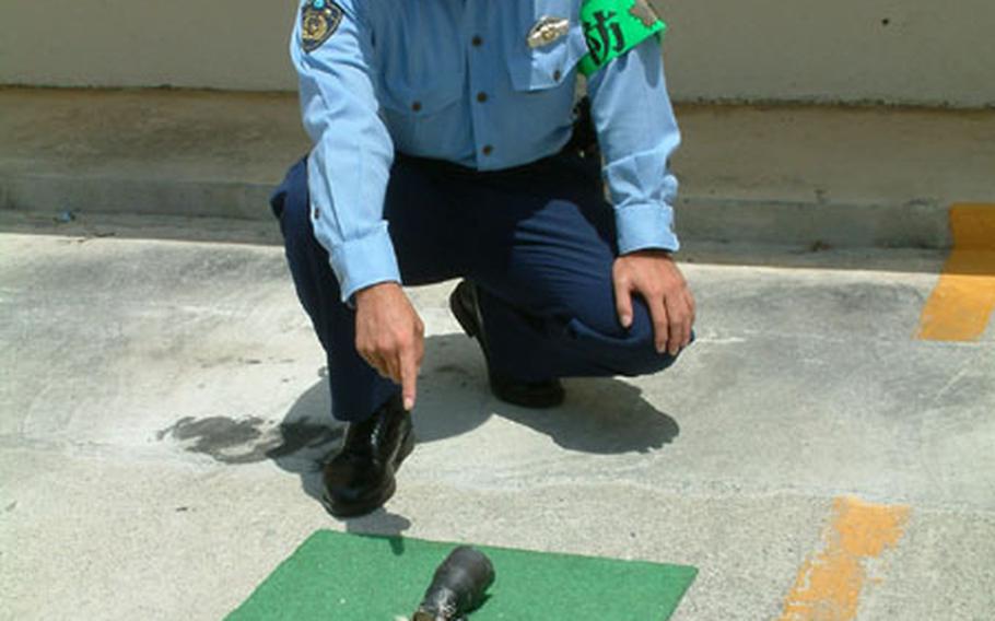 An Okinawa police officer points to a rocket-propelled grenade that was disabled Saturday morning in a densely populated Naha neighborhood.
