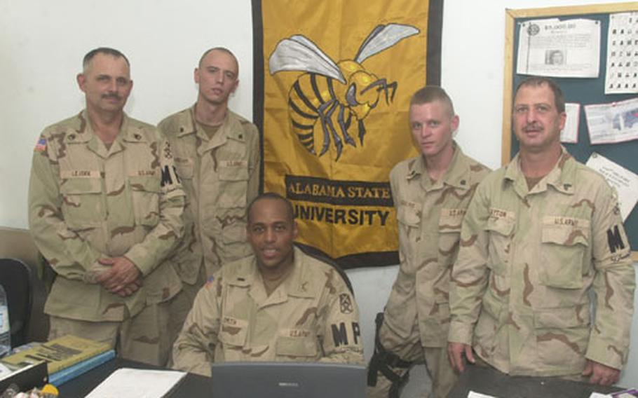 1st Lt. Herbert Smith poses with his soldiers from the 1165th Military Police Company with the banner of his alma mater, Alabama State University, hanging on the wall of their al-Dorah police station. From left to right are Staff Sgt. Carl Lejsek, Spc. Wesley Fendley, Smith, Spc. Eddie Jerkins and Sgt. Brad Deyton.