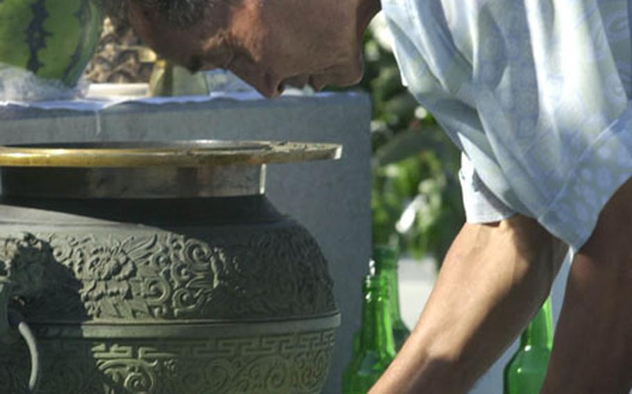 A man pours soju — a traditional Korean alcohol — before a monument honoring relatives still in North Korea on Chusok in September 2002. He was at Imjingak just shy of the North Korean border. Most Koreans travel to their hometowns during the three-day holiday — in effect, five days this year because it falls near the weekend — to visit relatives.