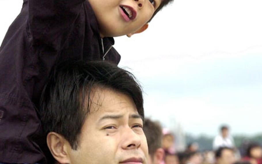 A young Japanese boy on his father&#39;s shoulders enjoying the Japanese Air Self-Defense Force&#39;s Blue Impulse Jr. aerial demonstration team at Misawa Air Base.