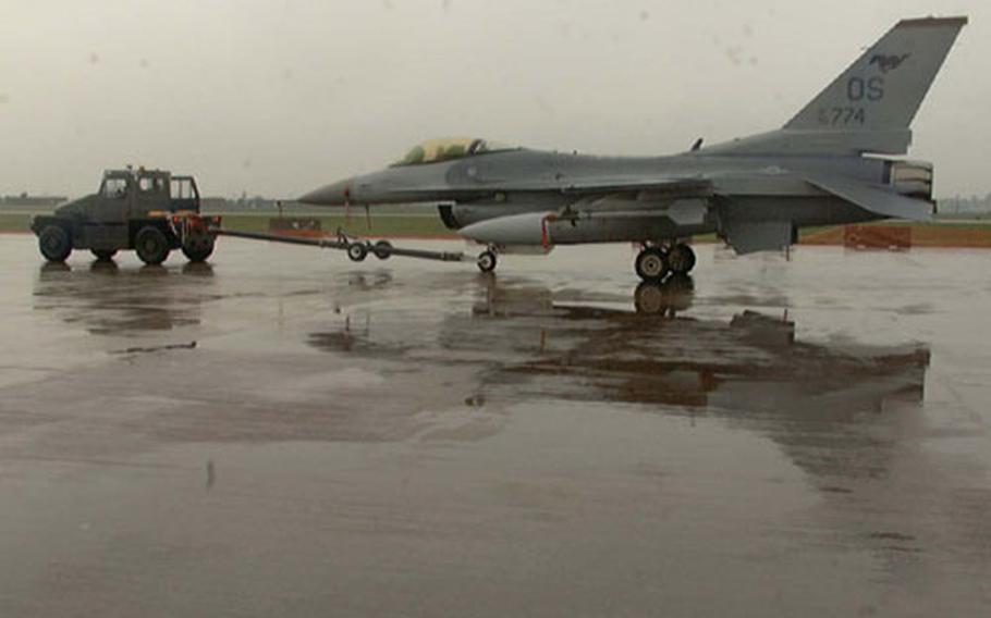 Ground crewmen tow an F-16 Fighting Falcon from the flight line at Osan Air Base, South Korea, where it had been set out for display in what would have been the base&#39;s second annual Air and Space Power Day air show. Base officials had to cancel the event because of bad weather.