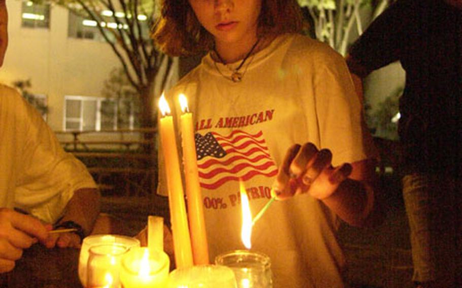 Kameryn Sanchez lights a candle at the Yokota Patriots Day Memorial Service held a Yokota Air Base Thursday.