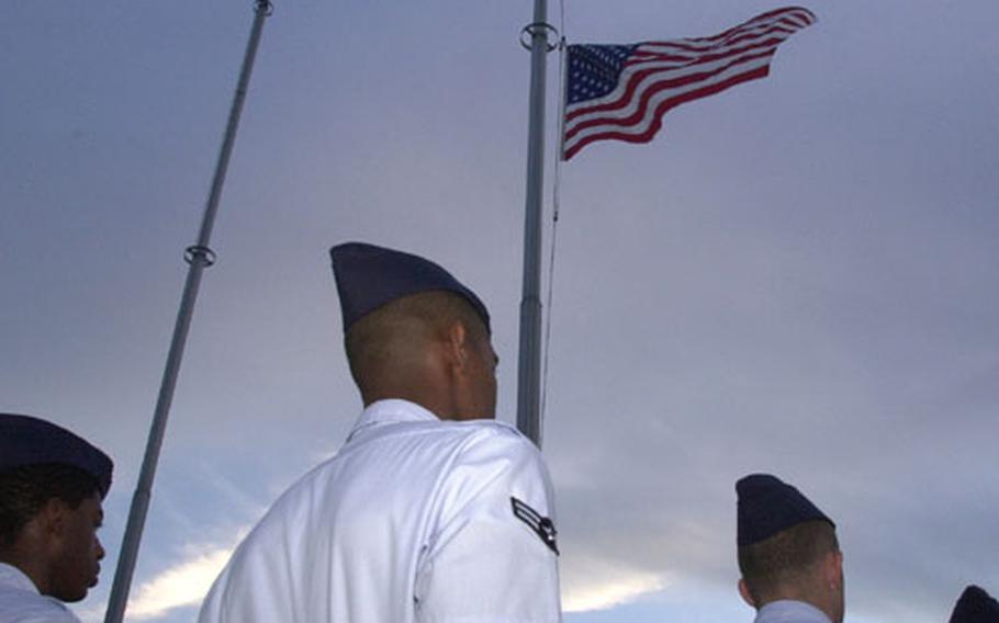 Airman at Yokota Air Base face the United States flag hanging at half-staff during the Yokota Patriots Day Memorial Service.