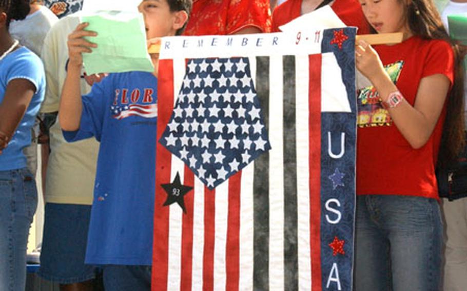 Students from Arnn Elementary school at Camp Zama&#39;s Sagamihara Housing Area sing "America the Beautiful" during a 9-11 Remembrance Ceremony Thursday. The flag some of the students are holding was designed by Arnn students, and each element represents a significant event of the day&#39;s tragedies, from the collapse of the World Trade Center to the heroic actions of the passengers of Flight 93.