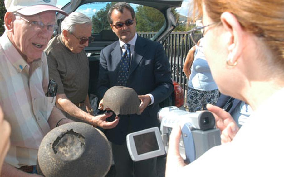 Former 36th Infantry Division soldier J.W. Hawkins, left, holds an American soldier&#39;s helmet found near San Pietro Infine by Fabrizio Carloni, center right, who holds a helmet liner. Looking at the liner is another former division member, Joseph Heiser. Carloni has written a book on the 1943 battle of San Pietro Infine, which Hawkins and Heiser took part in. In the foreground with the video camera is Hawkins&#39; daughter, Janet.